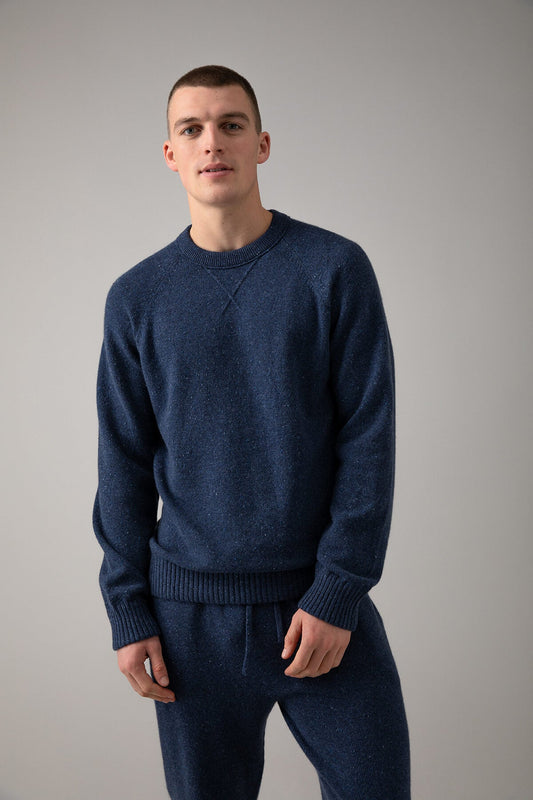 Johnstons of Elgin’s Men's Cashmere Donegal Sweatshirt in Denim blue on model wearing matching blue joggers on a grey background KAA05147004544