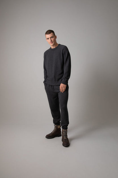 Johnstons of Elgin’s Men's Cashmere Donegal Joggers in Charcoal grey on model wearing matching grey cashmere jumper on a grey background KAI05146004521