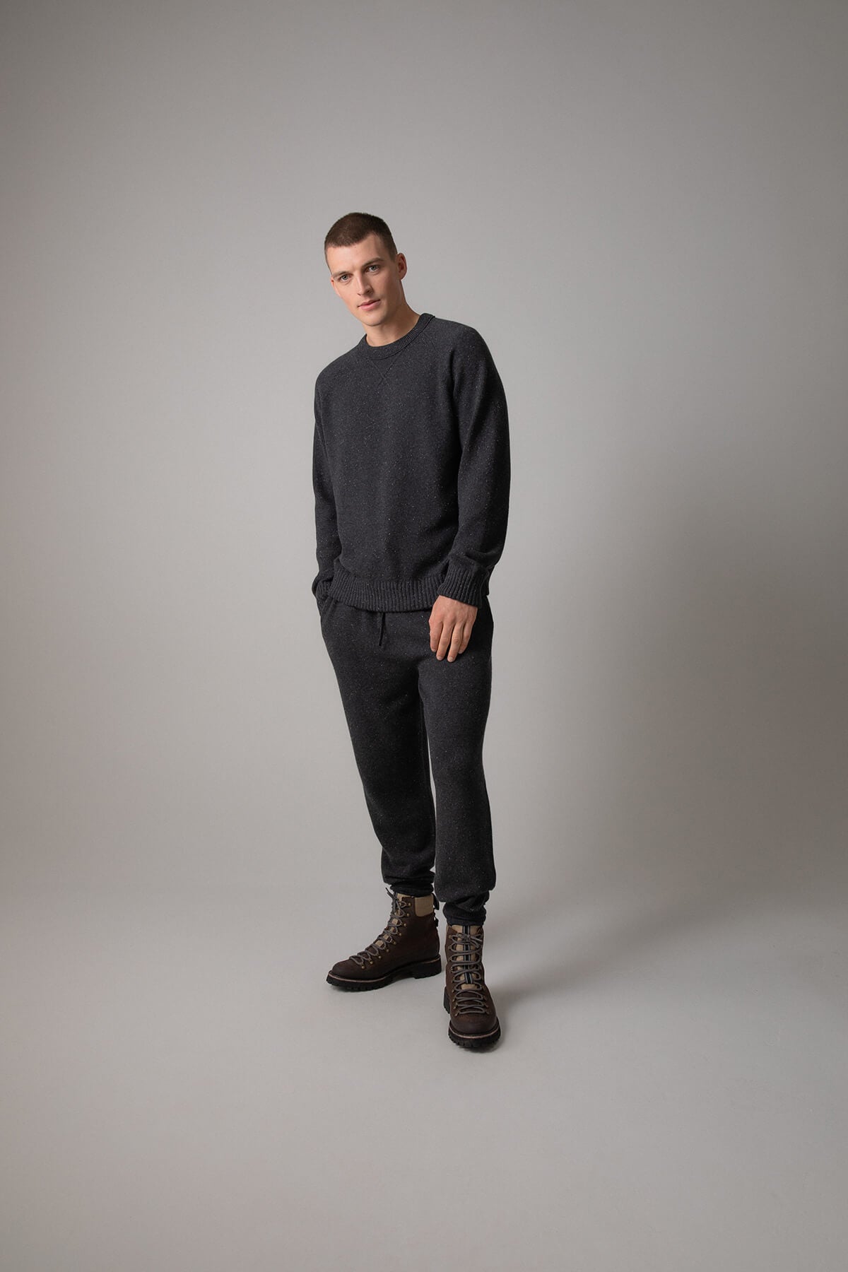 Johnstons of Elgin’s Men's Cashmere Donegal Sweatshirt in Charcoal grey on model wearing matching grey joggers on a grey background KAA05147004521