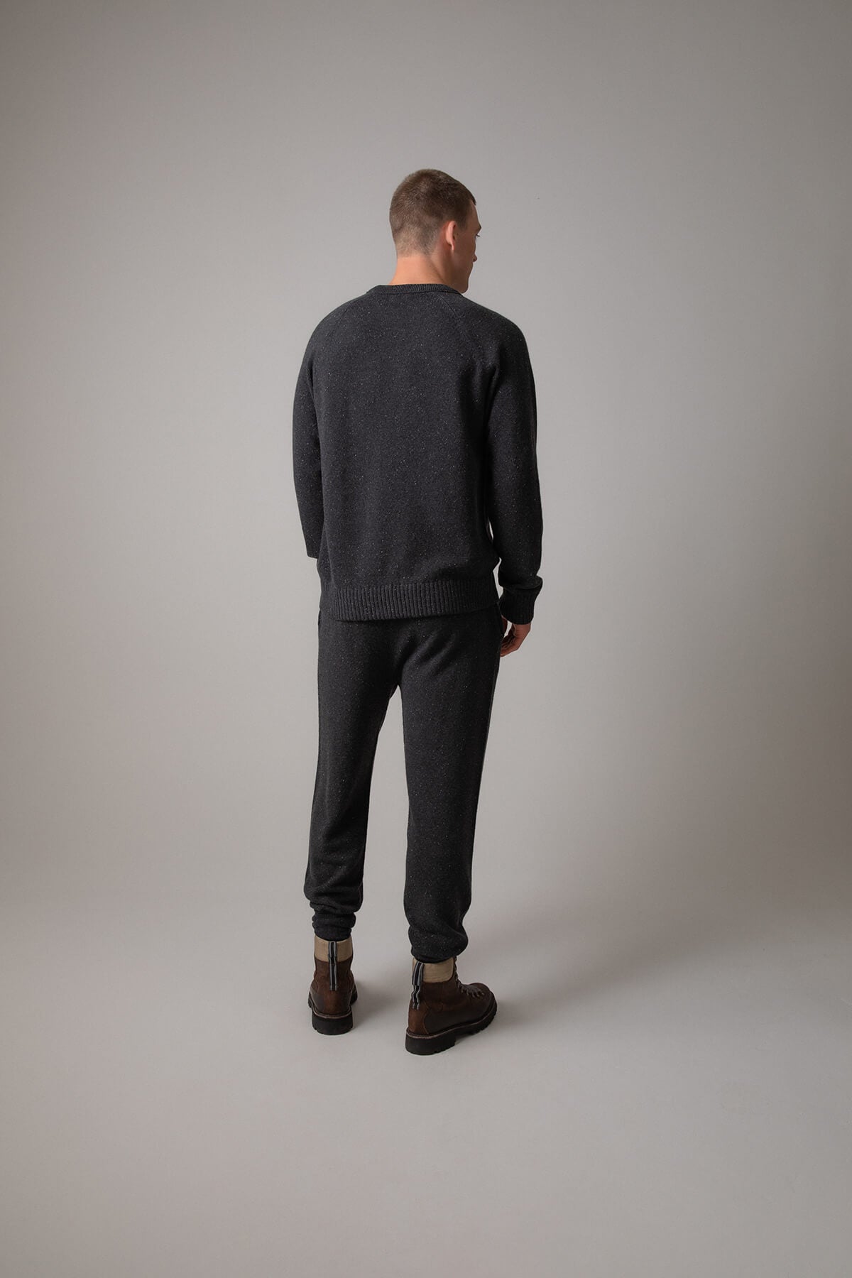 Johnstons of Elgin’s Men's Cashmere Donegal Joggers in Charcoal grey on model wearing matching grey cashmere jumper on a grey background KAI05146004521