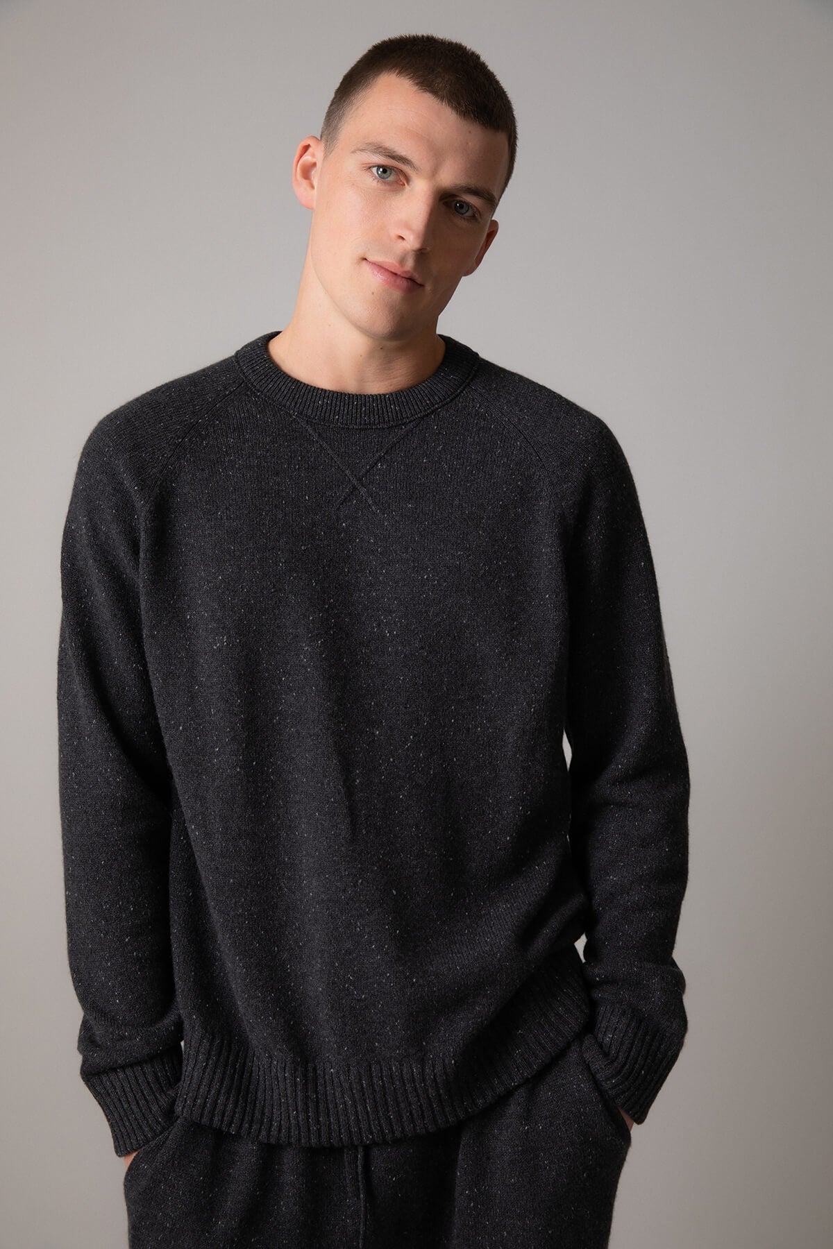 Johnstons of Elgin’s Men's Cashmere Donegal Sweatshirt in Charcoal grey on model wearing matching grey joggers on a grey background KAA05147004521