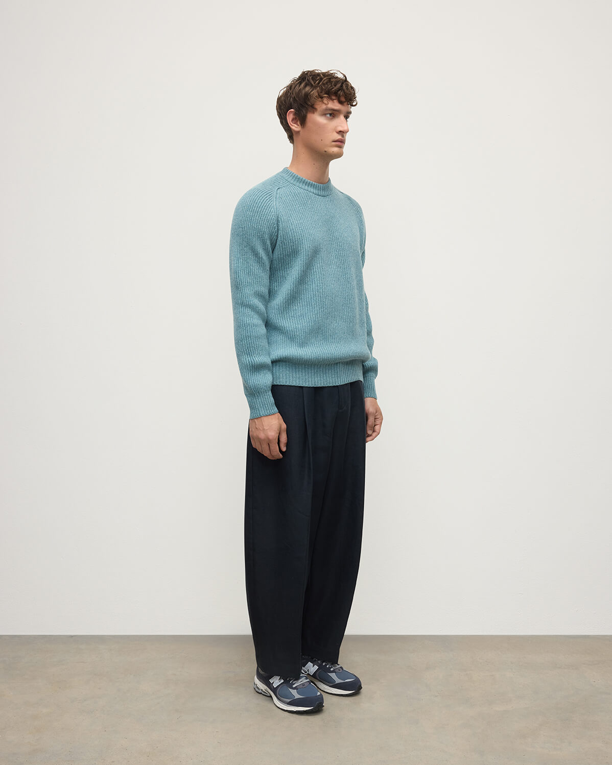 Side view of a model wearing Johnstons of Elgin AW25 Men's Knitwear Seascape & Light Grey Contrast Neck Green Cashmere Jumper KAA05270Q25365