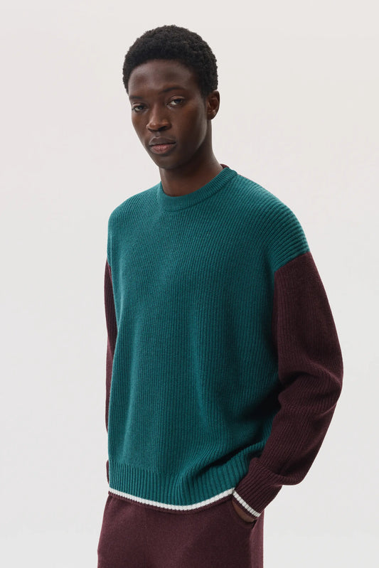 Model wears Johnstons of Elgin SS25 Men's Knitwear Rosewood & Emerald Colour Block Relaxed Cashmere Jumper with rosewood cashmere joggers KAA05412Q25137