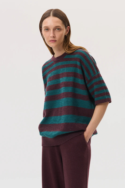 Female model wearing Johnstons of Elgin SS25 Unisex Knitwear Rosewood & Emerald Striped Oversized Cashmere T-Shirt on a white background KAA05414Q25125