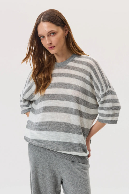 Female model wearing Johnstons of Elgin SS25 Unisex Knitwear Light Grey & White Textured Stripe Oversized Cashmere T-Shirt on a white backdrop KAA05414Q25124