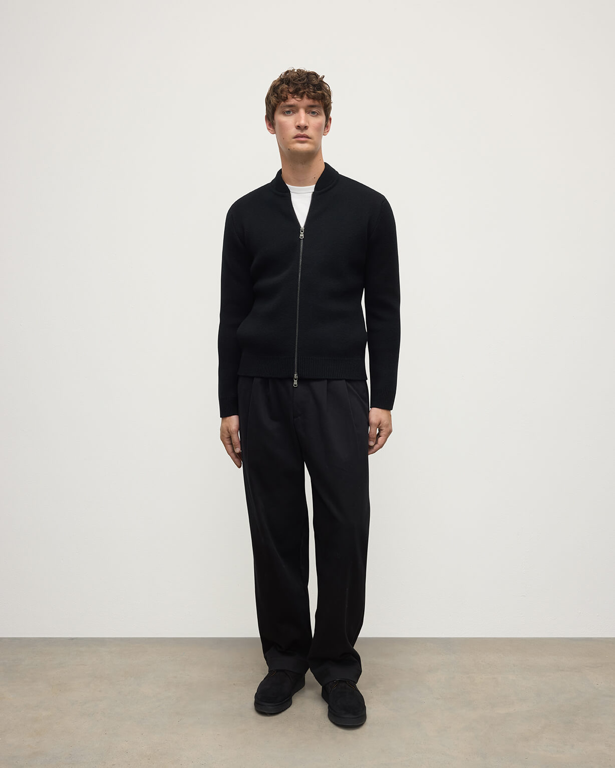 Johnstons of Elgin AW25 Men's Knitwear Black Cashmere Milano Stitch Zip Jacket with black trousers and a white t-shirt  KAA05443SA0900
