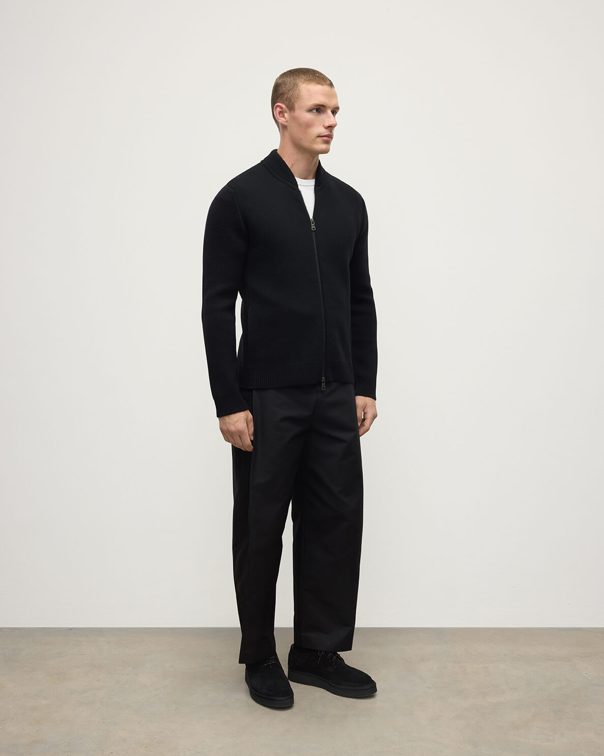 Side view of a model wearing Johnstons of Elgin AW25 Men's Knitwear Black Milano Ribbed Zip Black Cashmere Cardigan KAA05443SA7210
