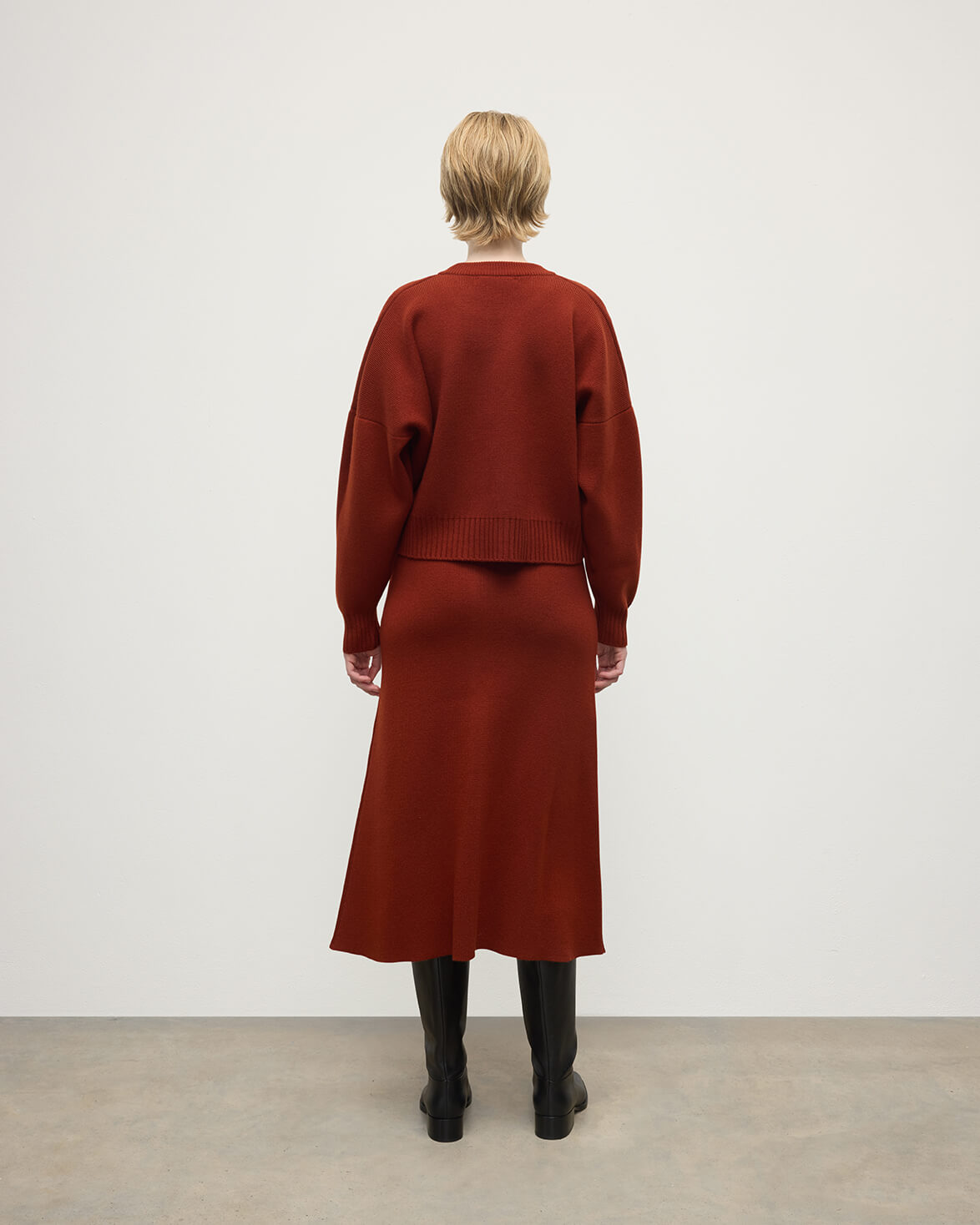 Model wears Johnstons of Elgin AW25 Women's Knitwear Oxblood A-Line Milano Red Cashmere Skirt Back View KAA05600SG4463