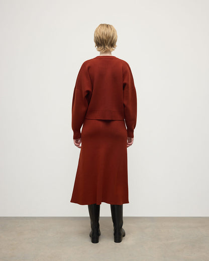 Model wears Johnstons of Elgin AW25 Women's Knitwear Oxblood A-Line Milano Red Cashmere Skirt Back View KAA05600SG4463
