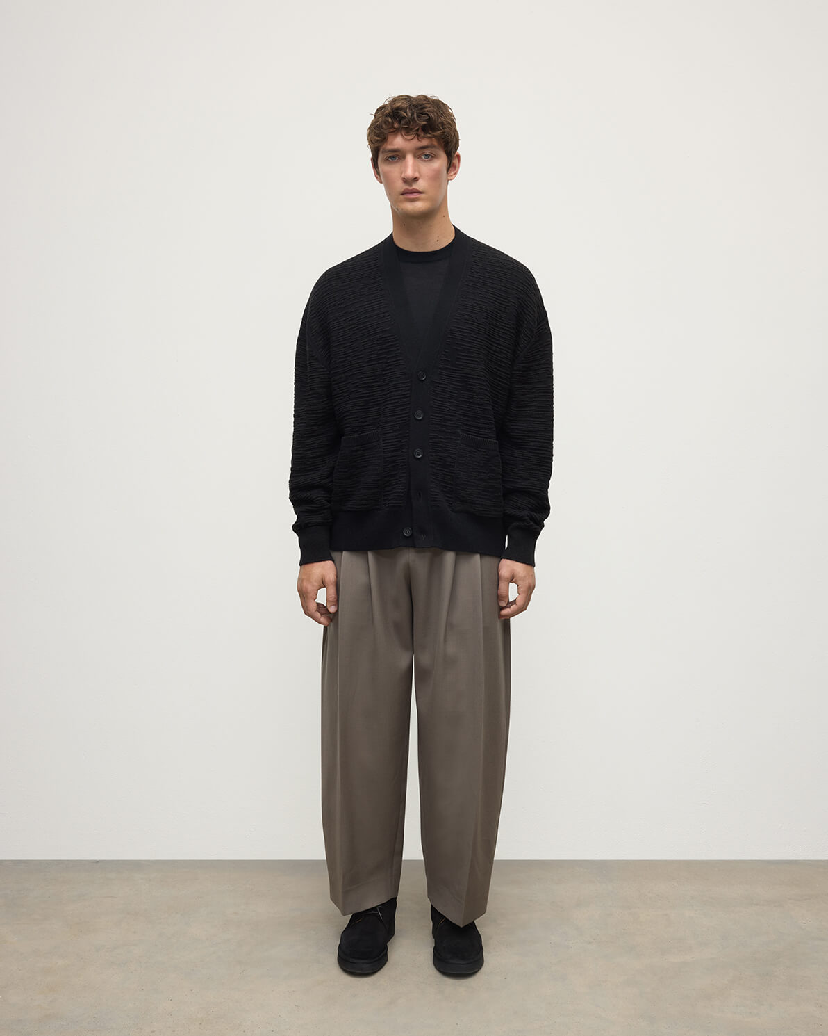 Model wearing Johnstons of Elgin AW25 Men's Knitwear Black & Iron Plaited Texture Black Cashmere Cardigan Front View KAA05579Q25387