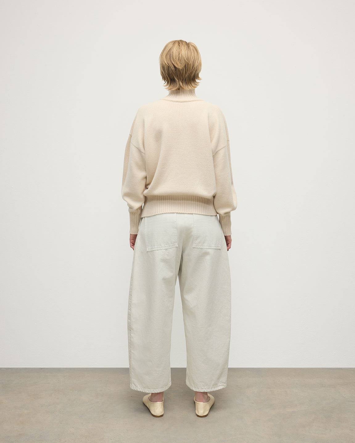 Model wearing Johnstons of Elgin AW25 Women's Knitwear Champagne High Neck Cream Cashmere Jumper Back View  KAA05585SA0502