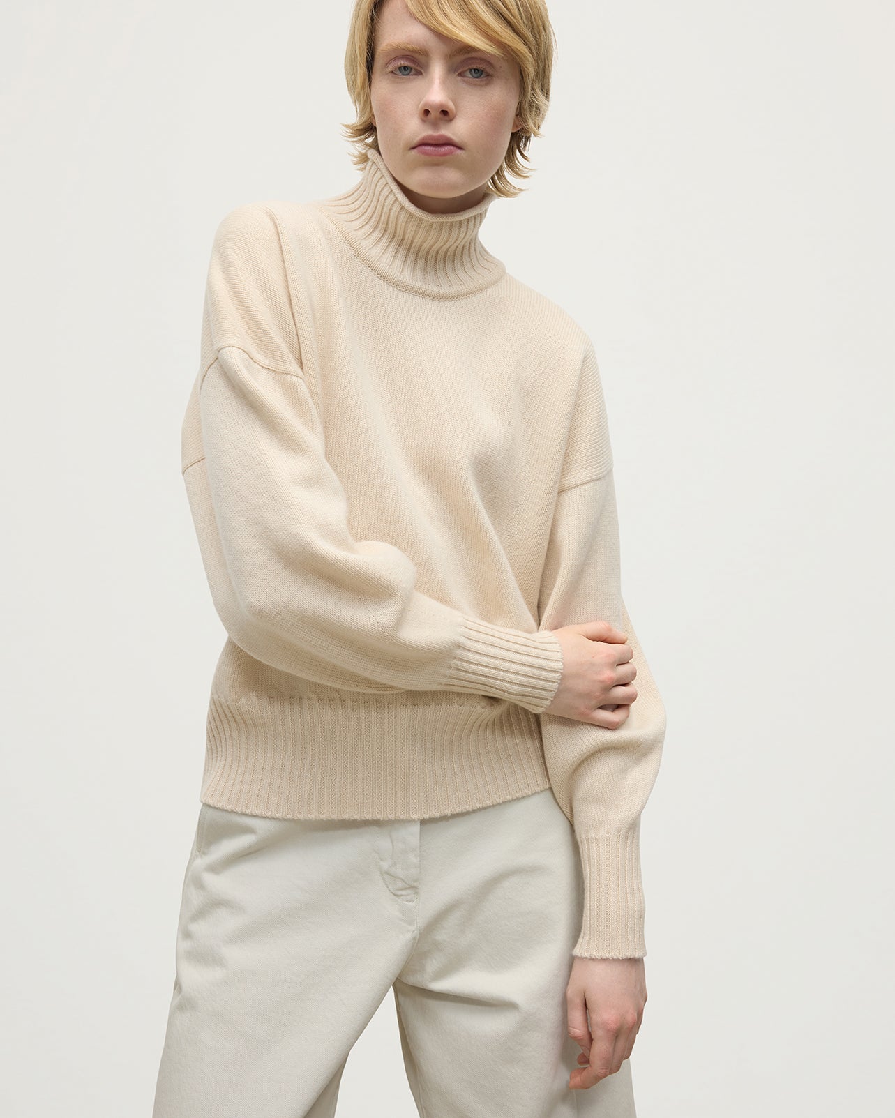Model wearing Johnstons of Elgin AW25 Women's Knitwear Champagne High Neck Cream Cashmere Jumper close up  KAA05585SA0502