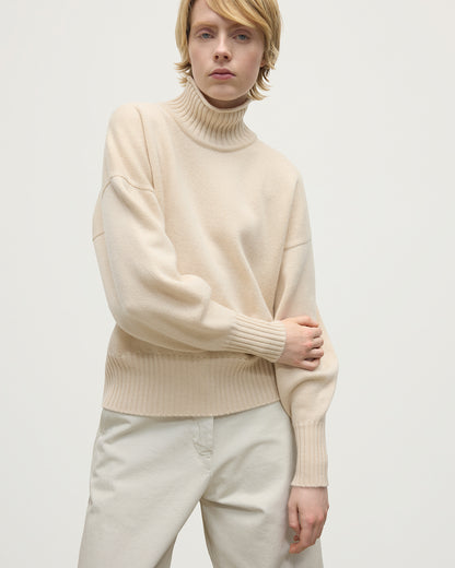 Model wearing Johnstons of Elgin AW25 Women's Knitwear Champagne High Neck Cream Cashmere Jumper close up  KAA05585SA0502