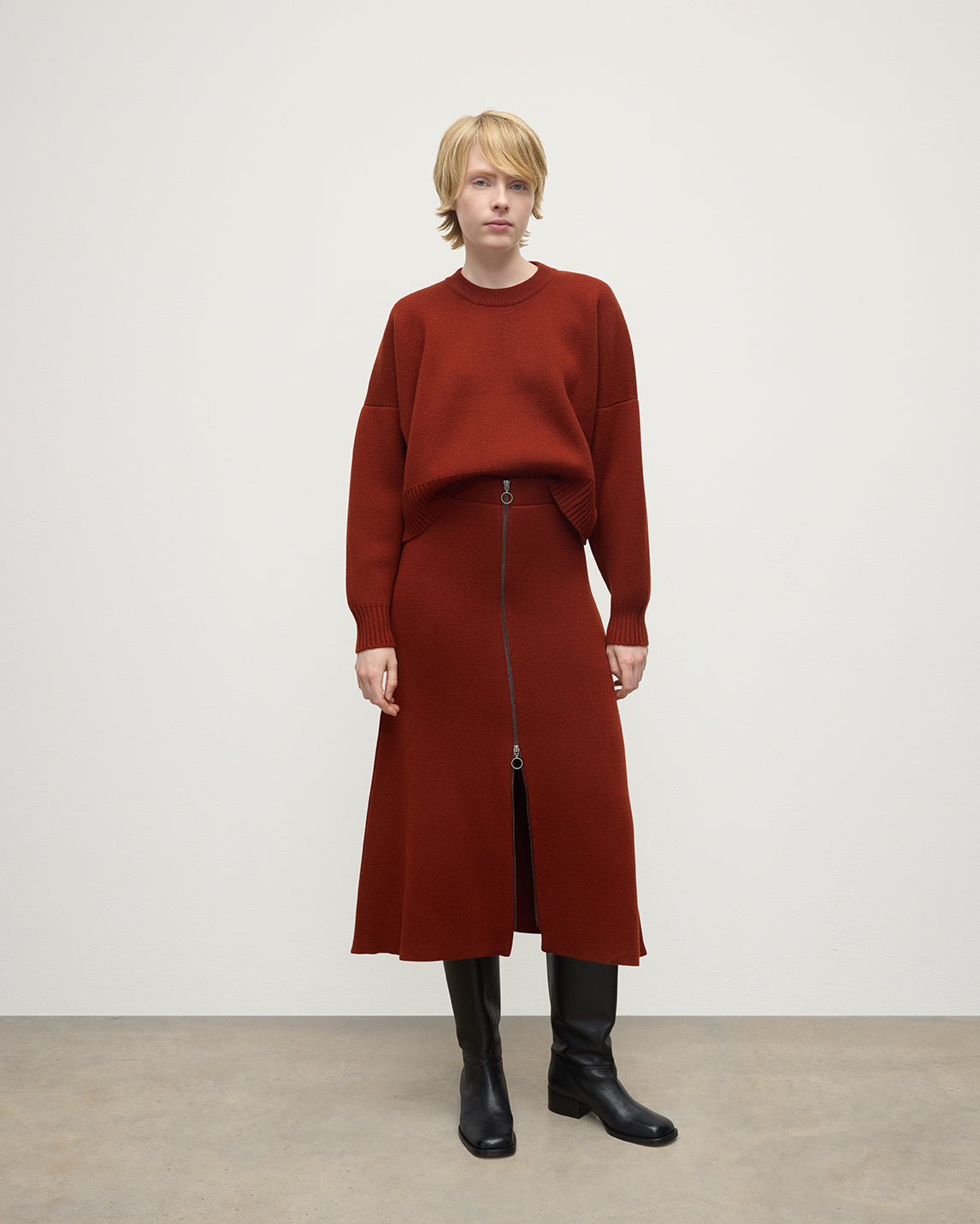 Model wears Johnstons of Elgin AW25 Women's Knitwear Oxblood A-Line Milano Red Cashmere Skirt Front View KAA05600SG4463