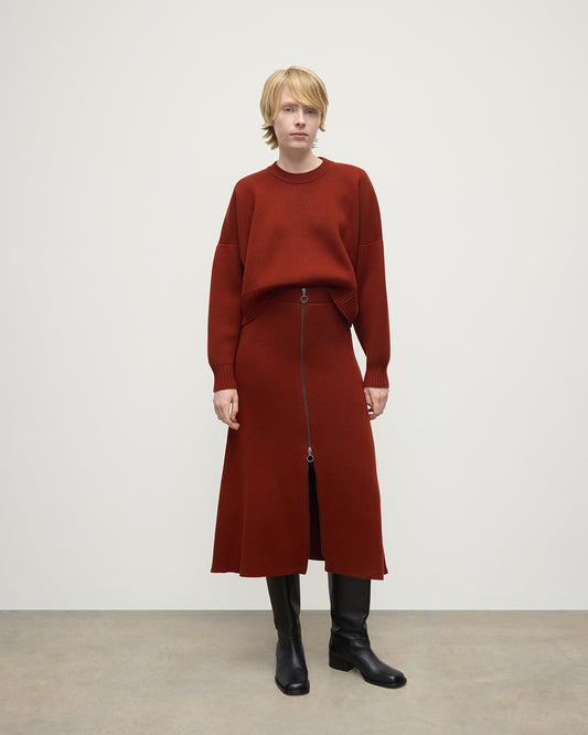 Model wears Johnstons of Elgin AW25 Women's Knitwear Oxblood A-Line Milano Red Cashmere Skirt Front View KAA05600SG4463