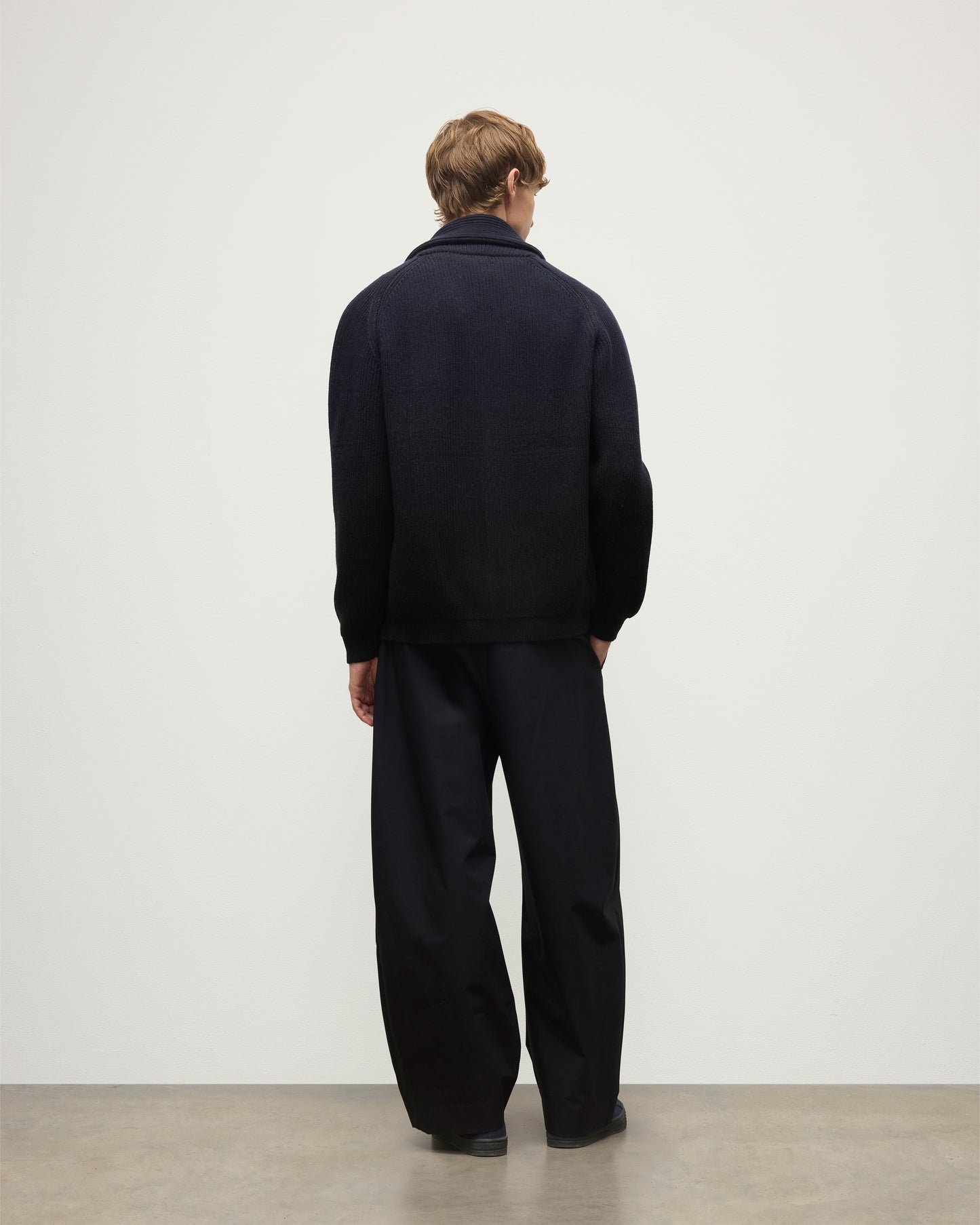 MALE MODEL WEARING JOHNSTONS OF ELGIN PIONEER SHAWL CARDIGAN NAVY & BLACK 100% CASHMERE WITH BLACK SUPERFINE CASHMERE SWEATER AND NAVY TROUSERS KAA05750Q25947