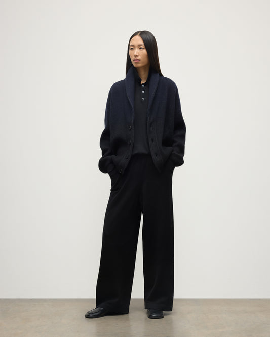 FEMALE MODEL WEARING JOHNSTONS OF ELGIN PIONEER SHAWL CARDIGAN NAVY & BLACK 100% CASHMERE WITH BLACK TROUSERS AND POLO SHIRT UAA05750Q25947