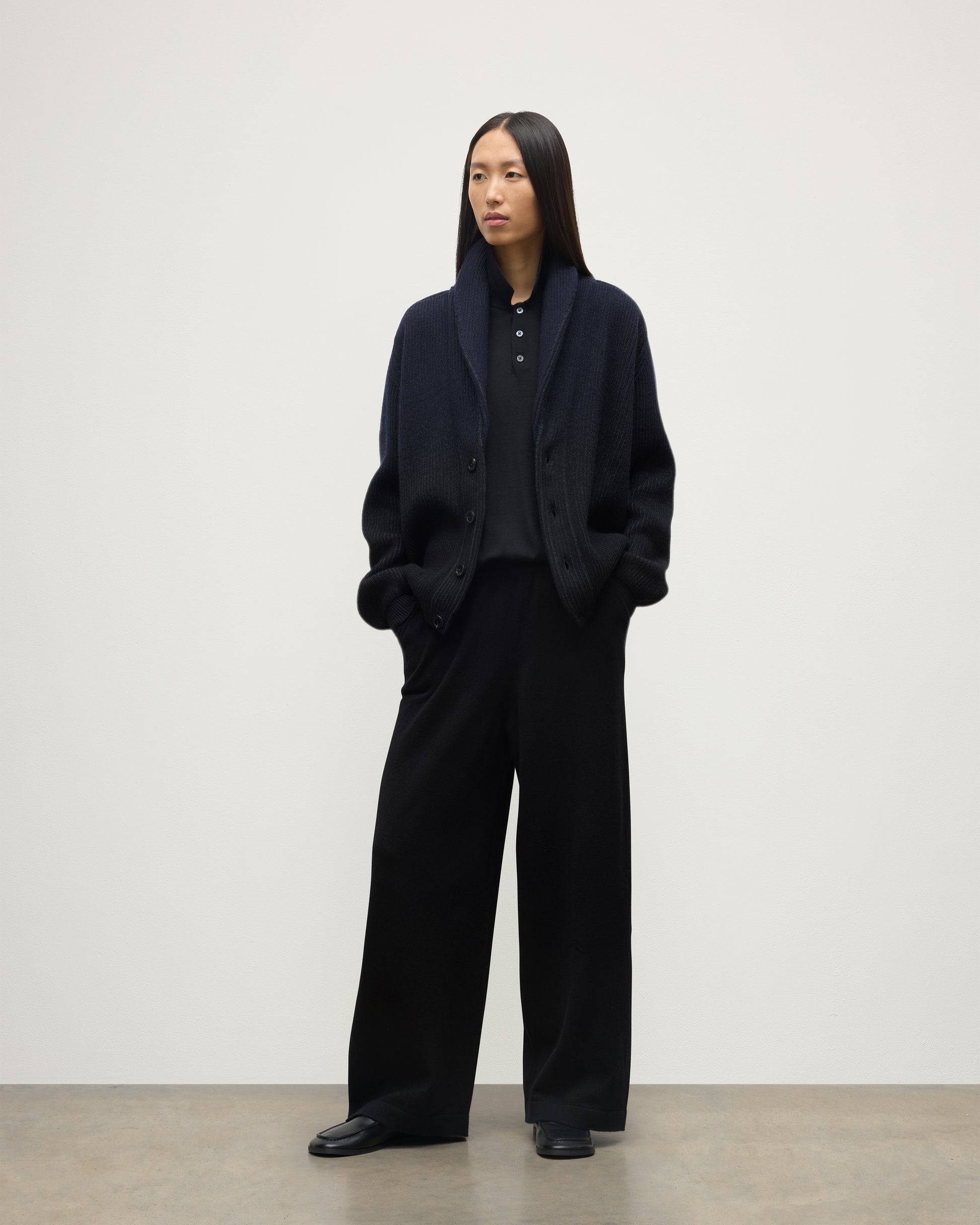 FEMALE MODEL WEARING JOHNSTONS OF ELGIN PIONEER SHAWL CARDIGAN NAVY & BLACK 100% CASHMERE WITH BLACK TROUSERS AND POLO SHIRT UAA05750Q25947