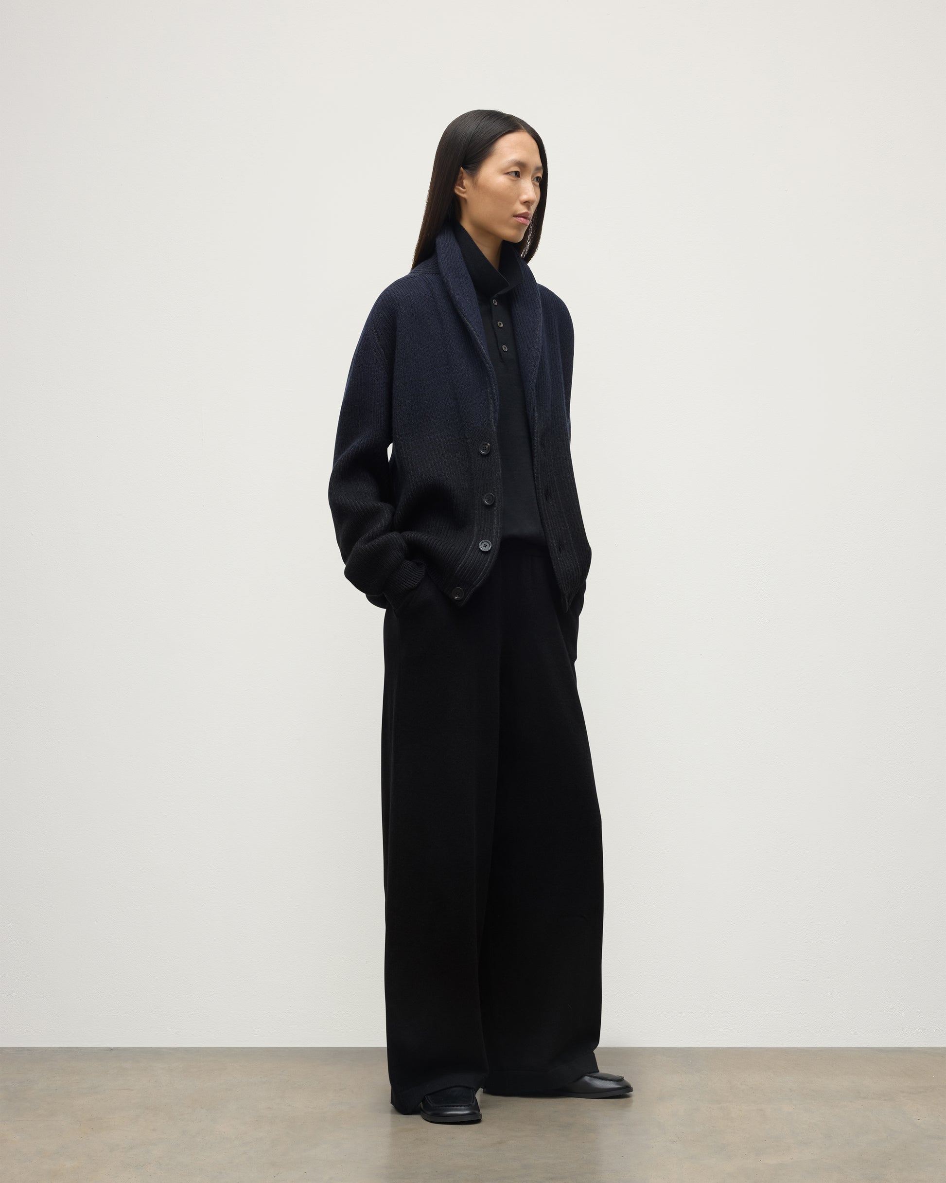 FEMALE MODEL WEARING JOHNSTONS OF ELGIN PIONEER SHAWL CARDIGAN NAVY & BLACK 100% CASHMERE WITH BLACK TROUSERS, SHOES AND POLO SHIRT UAA05750Q25947