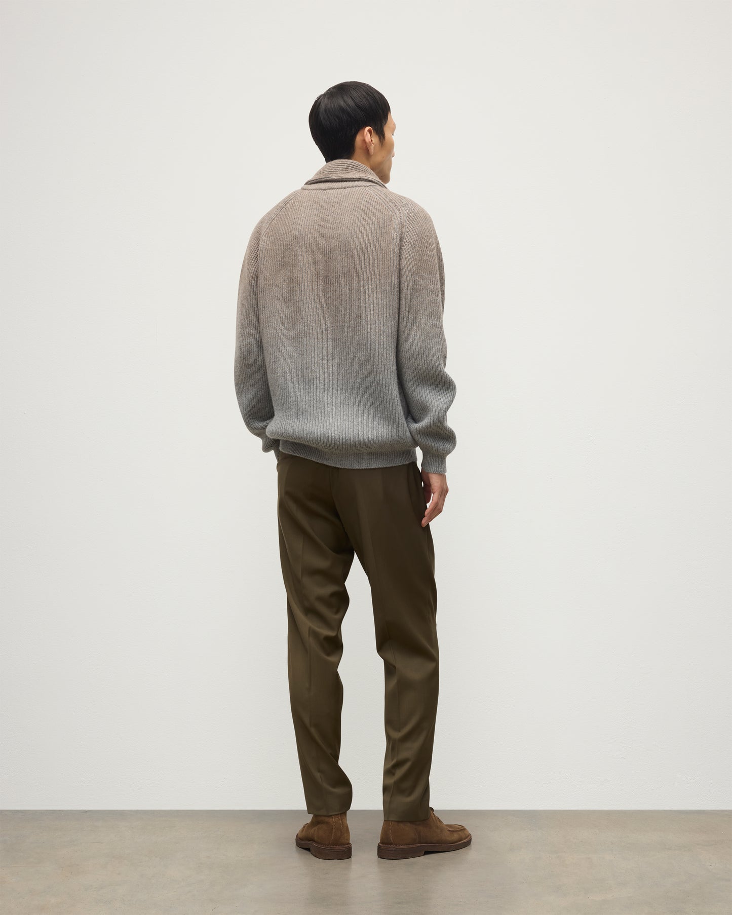 MALE MODEL WEARING JOHNSTONS OF ELGIN PIONEER SHAWL CARDIGAN GREY 100% CASHMERE WITH OLIVE GREEN CHINOS, OVER A SUPERFINE CASHMERE LIGHT BROWN SWEATER AND WHITE T-SHIRT KAA05750Q25948