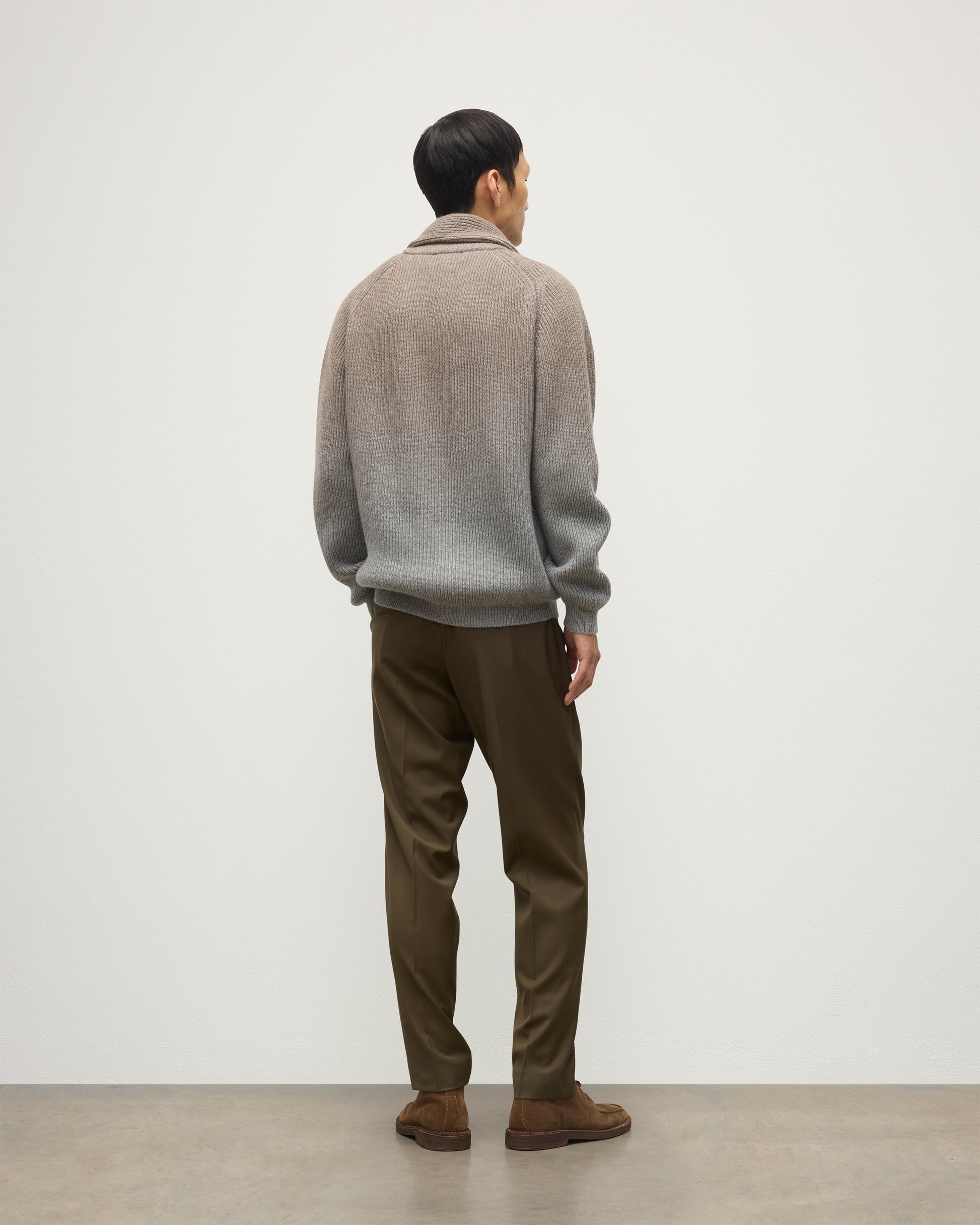 MALE MODEL WEARING JOHNSTONS OF ELGIN PIONEER SHAWL CARDIGAN GREY 100% CASHMERE WITH OLIVE GREEN CHINOS, OVER A SUPERFINE CASHMERE LIGHT BROWN SWEATER AND WHITE T-SHIRT KAA05750Q25948
