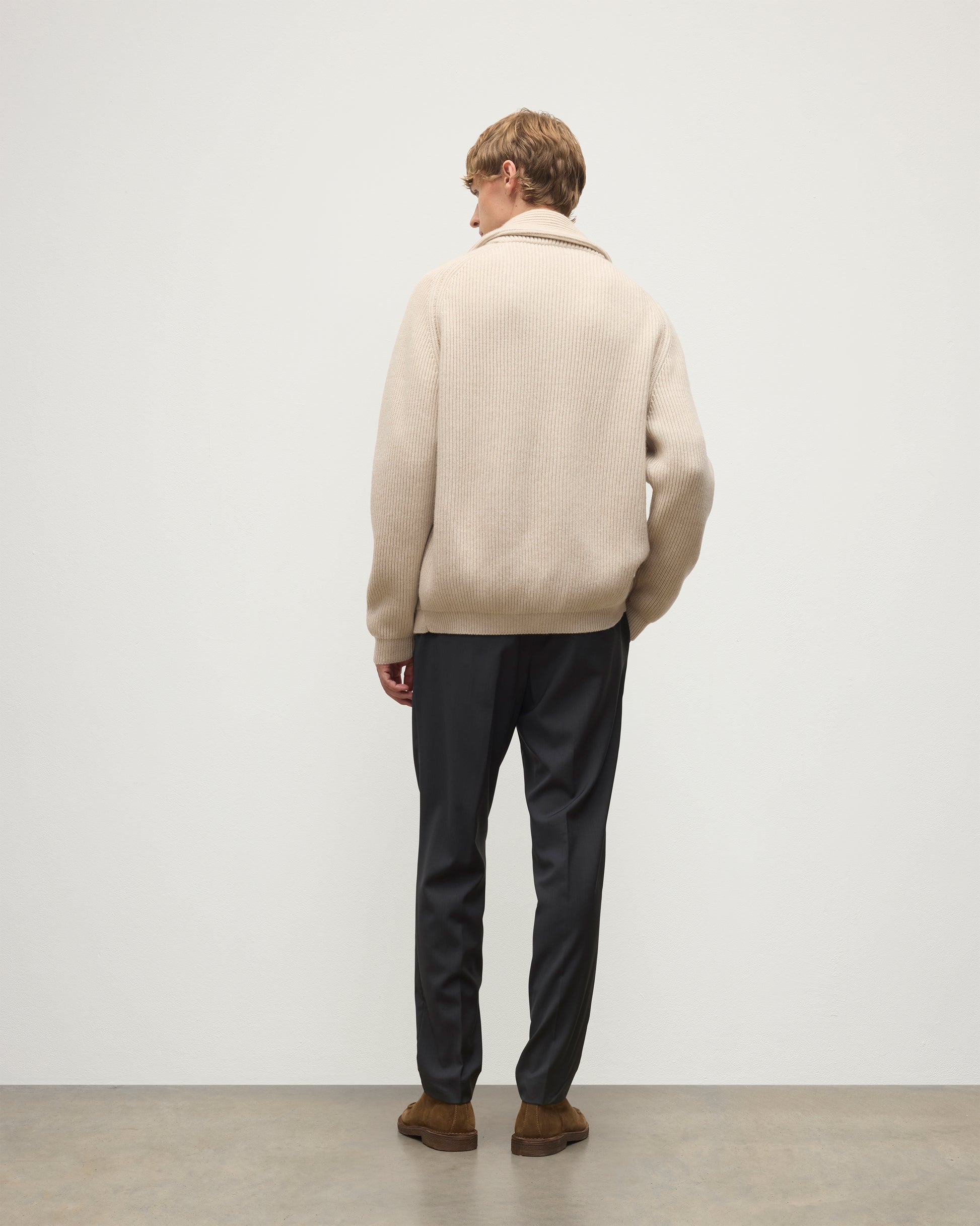 MALE MODEL WEARING JOHNSTONS OF ELGIN PIONEER SHAWL CARDIGAN NATURAL 100% CASHMERE OVER A CREAM CASHMERE SWEATER WITH GREY TROUSERS AND BROWN SUEDE LOAFERS KAA05750Q26191