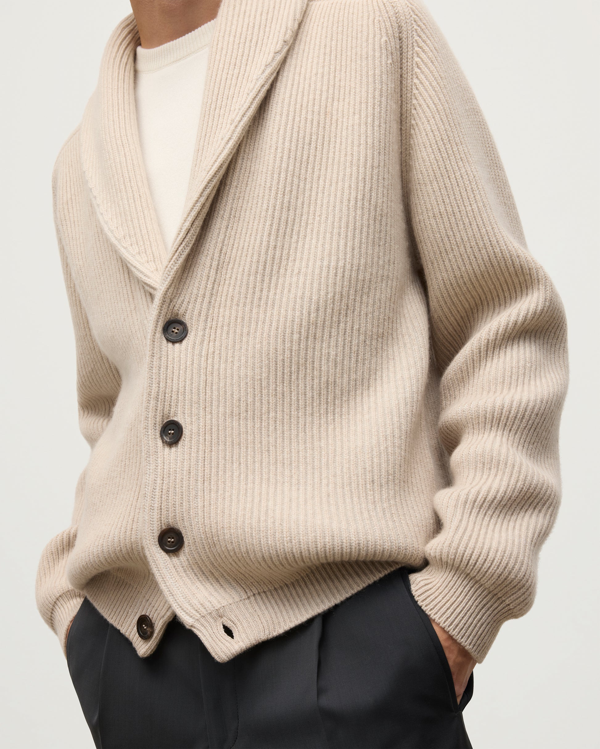 MALE MODEL WEARING JOHNSTONS OF ELGIN PIONEER SHAWL CARDIGAN NATURAL 100% CASHMERE OVER A CREAM CASHMERE SWEATER WITH GREY TROUSERS AND BROWN SUEDE LOAFERS KAA05750Q26191