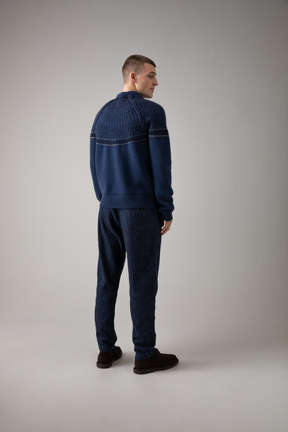 Johnstons of Elgin’s Men's Fairisle Yoke Cashmere Jumper in Ocean blue on model wearing blue trousers on a grey background KAB05108Q23716