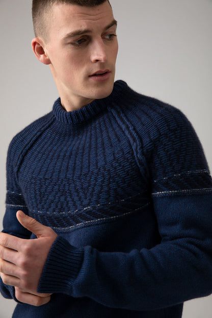 Johnstons of Elgin’s Men's Fairisle Yoke Cashmere Jumper in Ocean blue on model on a grey background KAB05108Q23716