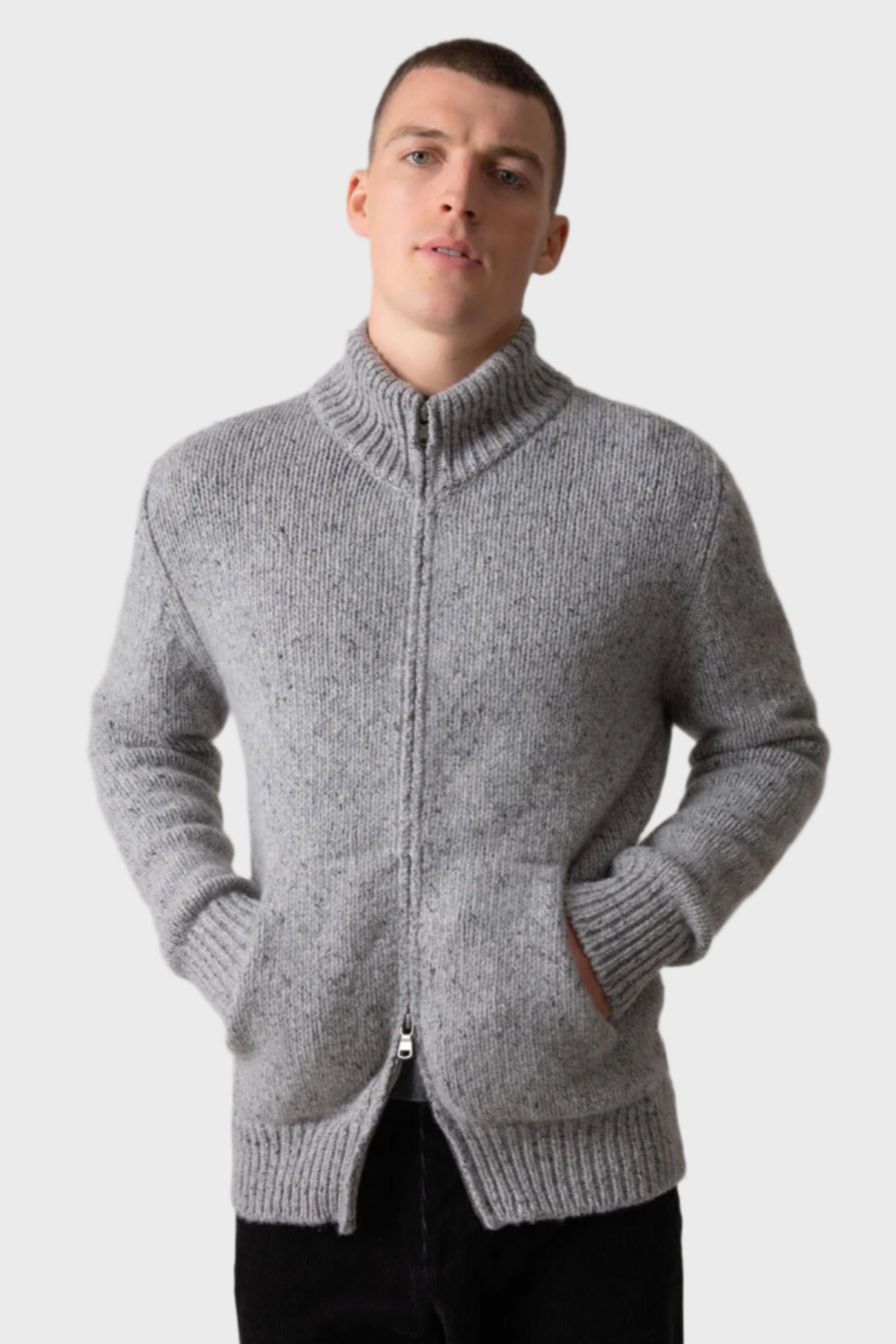 Johnstons of Elgin’s Men's Cashmere Donegal Zip Turtle Neck Cardigan in Light Grey on model wearing black trousers on a grey background KAB05115Q23711