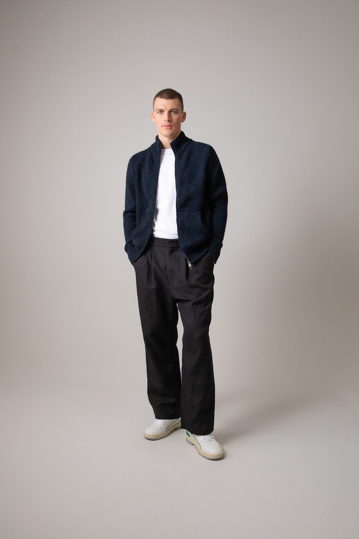 Johnstons of Elgin’s Men's Cashmere Donegal Zip Turtle Neck Cardigan in Dark Navy on model wearing black trousers on a grey background KAB05115Q23712