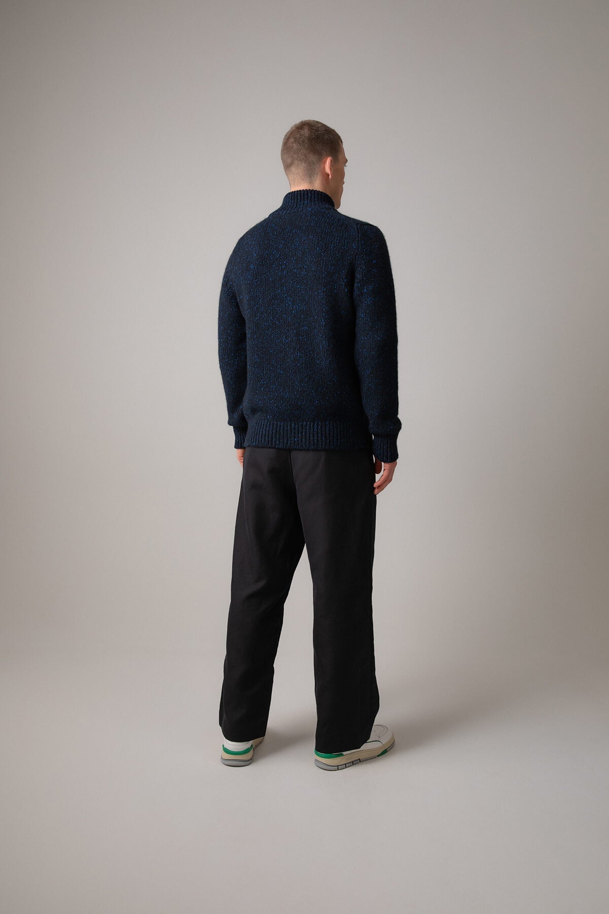 Johnstons of Elgin’s Men's Cashmere Donegal Zip Turtle Neck Cardigan in Dark Navy on model wearing black trousers on a grey background KAB05115Q23712