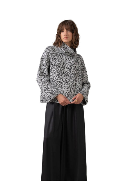 Johnstons of Elgin Women's Handknit Look Cashmere Marl Roll Neck Sweater in Black & White Marl worn with a Long Black Skirt on a grey background KAB05154HA7149