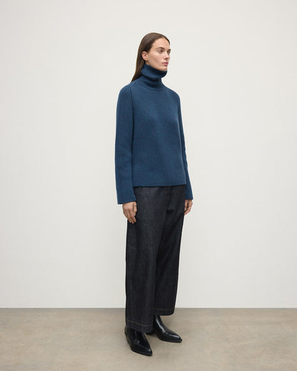 Model wears Johnstons of Elgin AW25 Women's Knitwear Heather Navy Roll-Collar Navy Cashmere Jumper Side View KAB05492HD7321