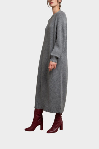 Side view of a Model wearing Johnstons of Elgin Women’s Cashmere Sweater Dress in Granite a grey background KAC05045HA5931