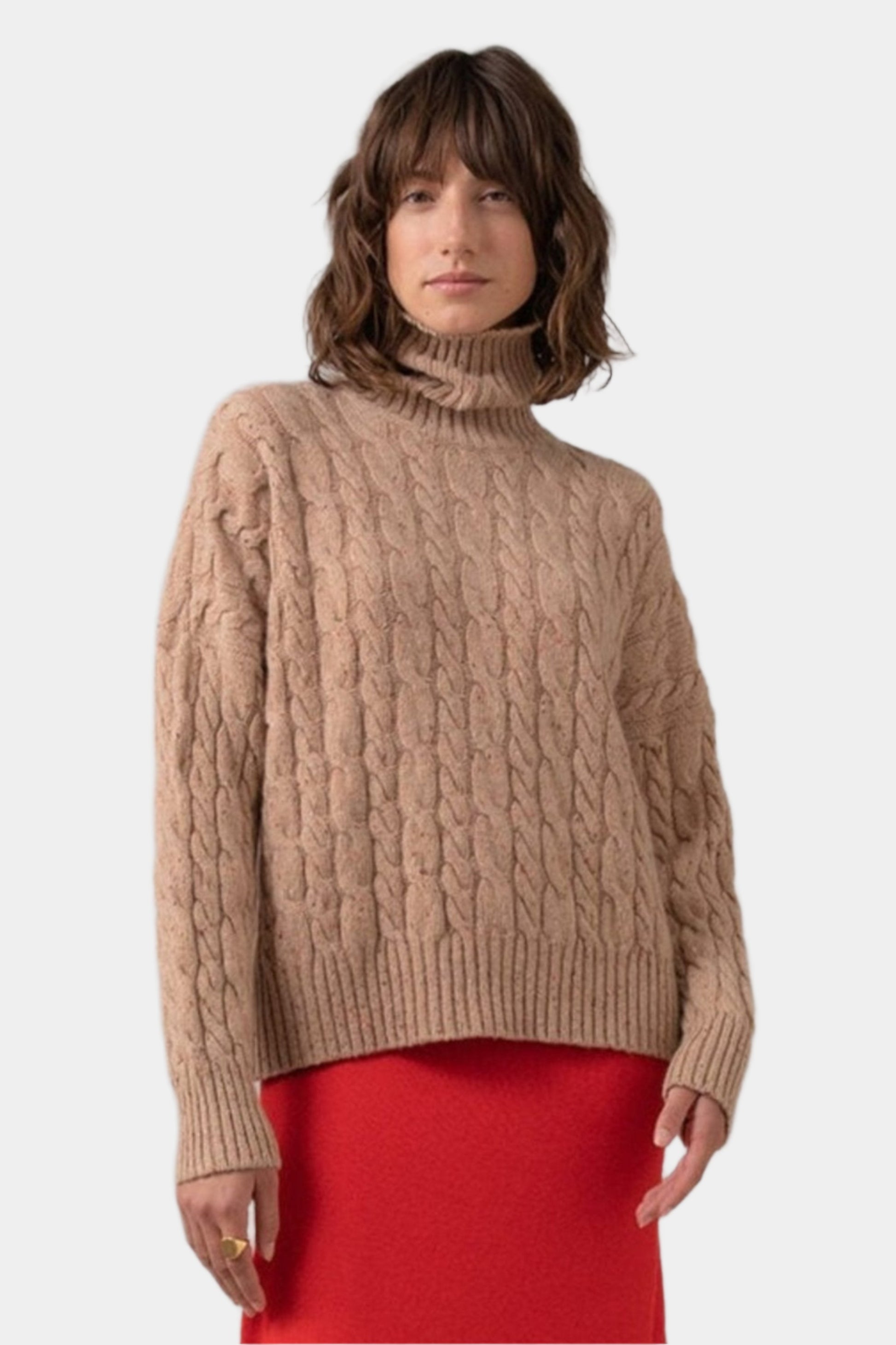 Johnstons of Elgin Women's Donegal Cashmere Cable Roll Neck Jumper in Camel Donegal worn with Red A-Line Skirt on a grey background KAC05091004507