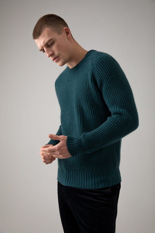 Johnstons of Elgin’s Men's Cashmere Ribbed Round Neck Jumper in Mallard green on model wearing black trousers on a grey background KAC05109HC7126