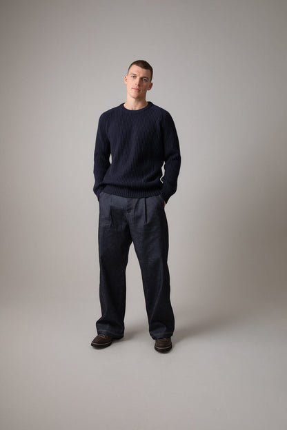 Johnstons of Elgin’s Men's Cashmere Ribbed Round Neck Jumper in Dark Navy on model wearing navy trousers on a grey background KAC05109SD7286