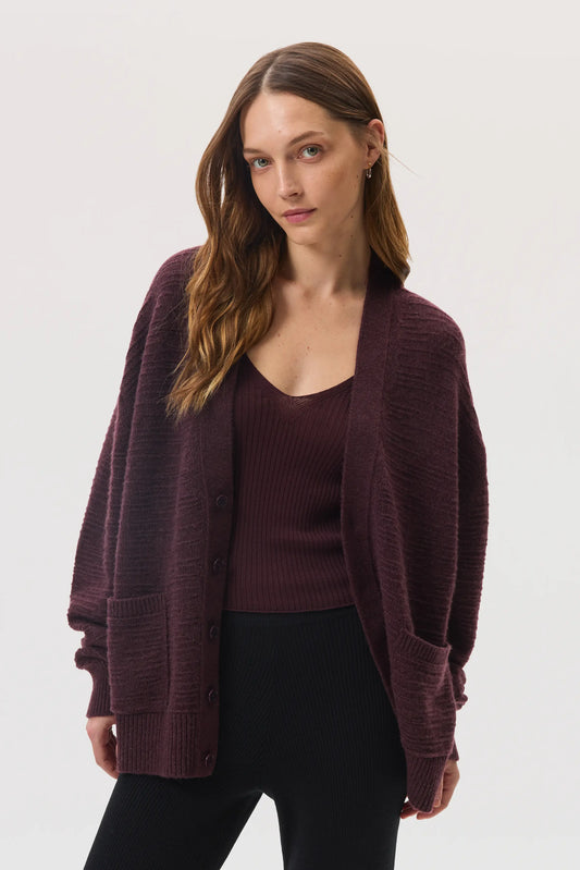 Female model wearing Johnstons of Elgin SS25 Unisex Knitwear Rosewood Textured Cashmere Cardigan with superfine cashmere vest, against a white background KAC05415SB7089