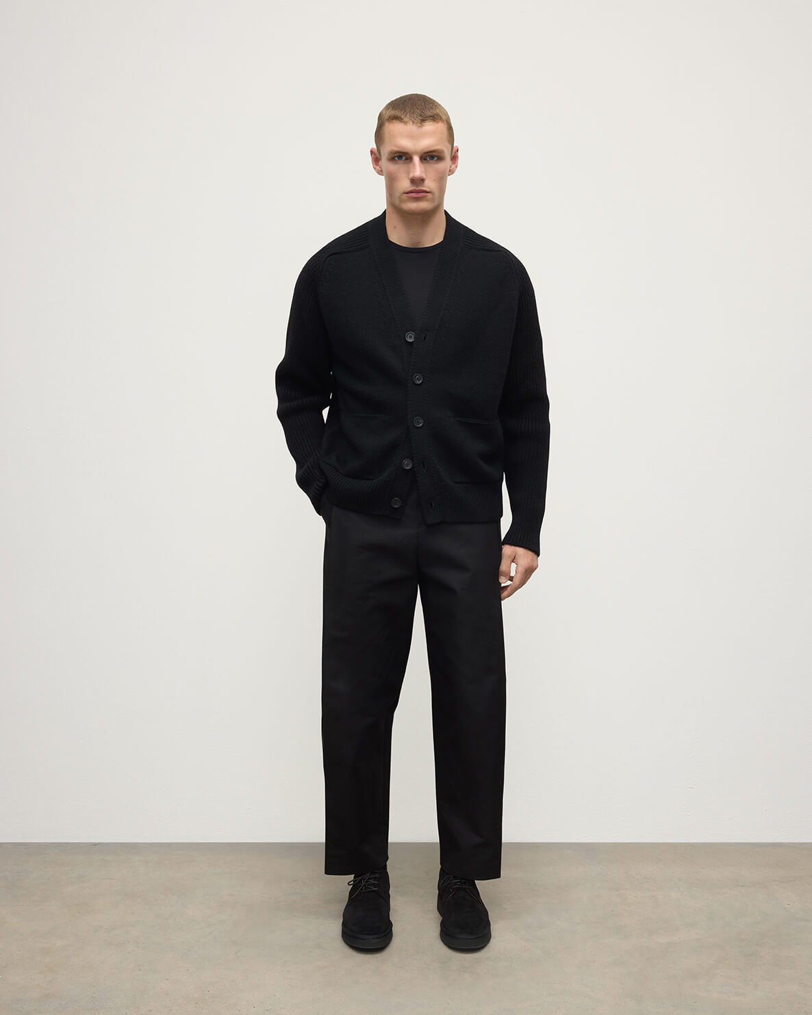 Johnstons of Elgin AW25 Men's Knitwear Black Ribbed Cashmere Black Cardigan worn over a black t-shirt with blank trousers KAC05601SA7210