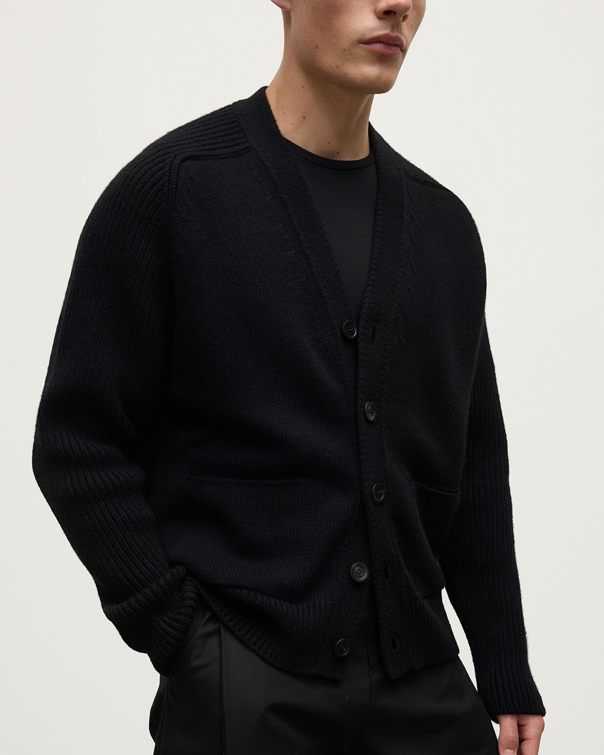 Johnstons of Elgin AW25 Men's Knitwear Black Ribbed Cashmere Black Cardigan worn over a black t-shirt, showing button details  KAC05601SA7210