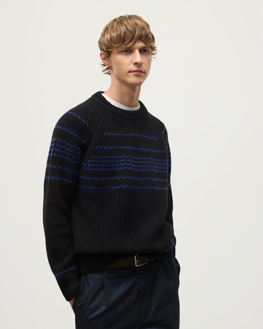 MODEL WEARS JOHNSTONS OF ELGIN  MENS SUMMIT CREW SWEATER BLACK & BLUE 100% CASHMERE OVER A WHITE T-SHIRT WITH NAVY TROUSERS KAC05752Q25949