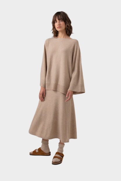 Johnstons of Elgin Boat Neck Cashmere Cape Jumper in Oatmeal worn with a matching A-Line Skirt on a grey background KAI05048HB0210