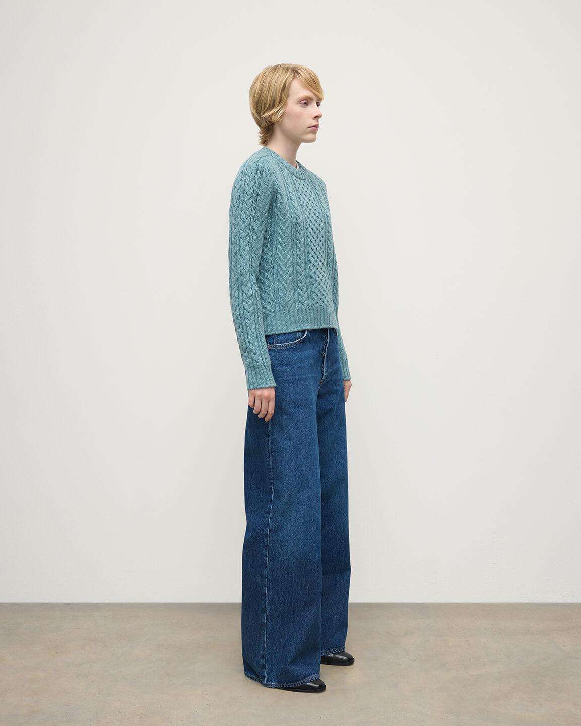 Model wears Johnstons of Elgin AW25 Women's Knitwear Seascape Aran Cable Green Cashmere Jumper Side View KAI05086HC0038