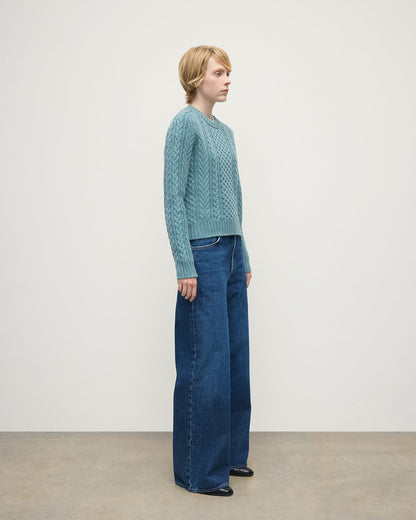 Model wears Johnstons of Elgin AW25 Women's Knitwear Seascape Aran Cable Green Cashmere Jumper Side View KAI05086HC0038