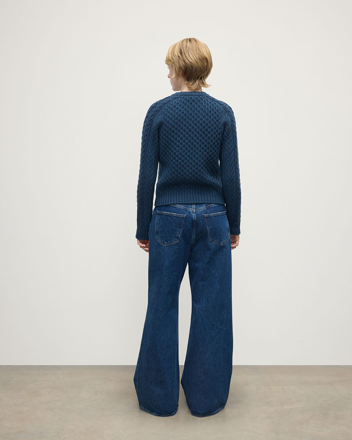 Model wears Johnstons of Elgin AW25 Women's Knitwear Heather Navy Aran Cable Navy Cashmere Jumper Back View KAI05086HD7321