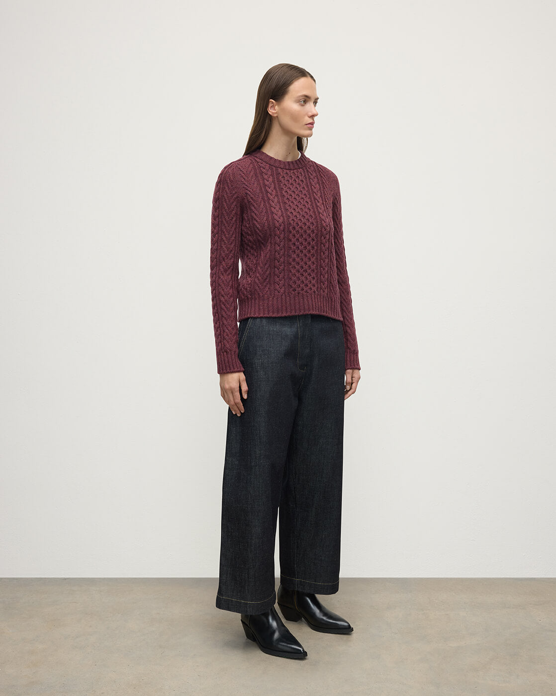 Model wears Johnstons of Elgin AW25 Women's Knitwear Damson Aran Cable Purple Cashmere Jumper  Side View KAI05086HE7064