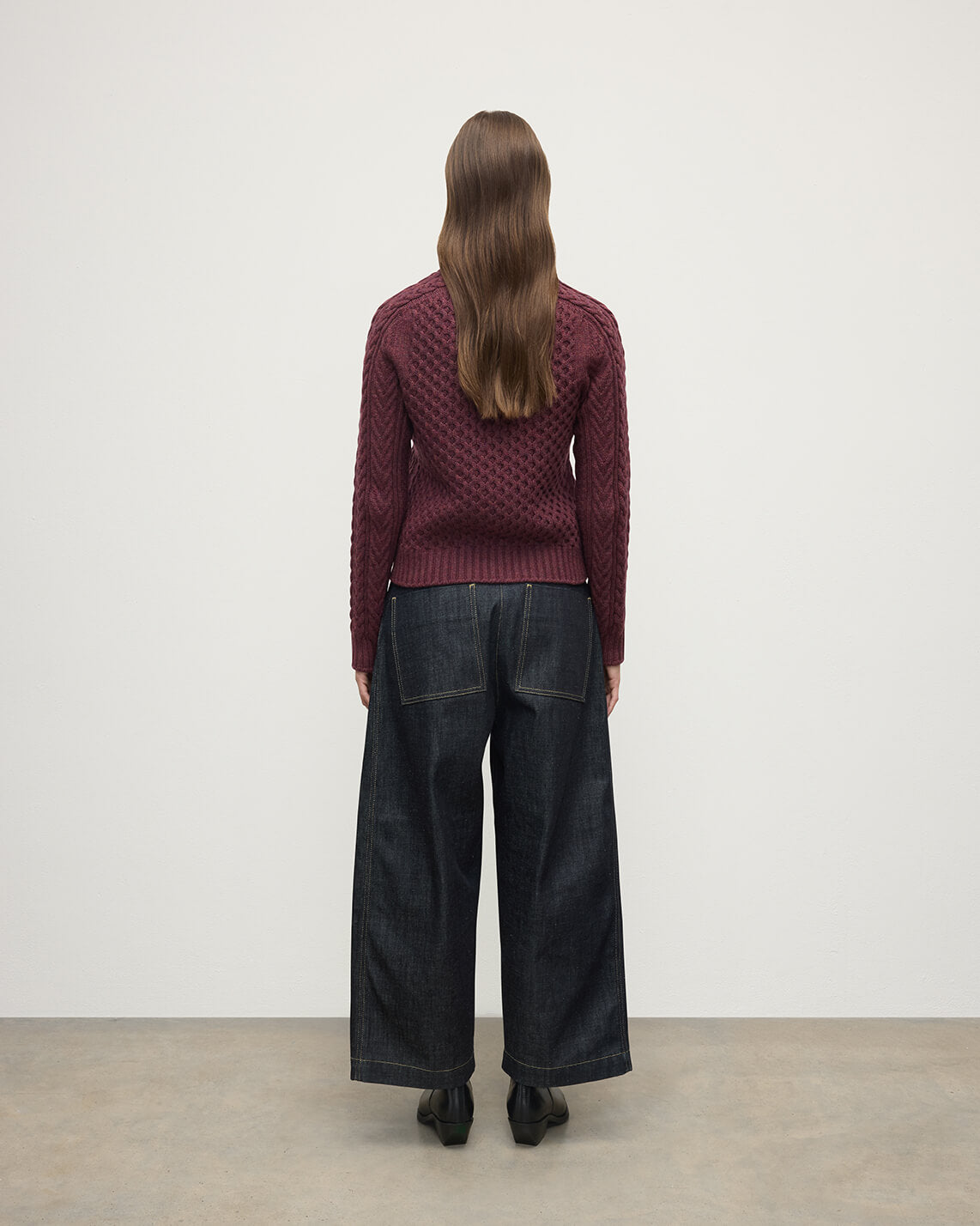 Model wears Johnstons of Elgin AW25 Women's Knitwear Damson Aran Cable Purple Cashmere Jumper  Back View KAI05086HE7064