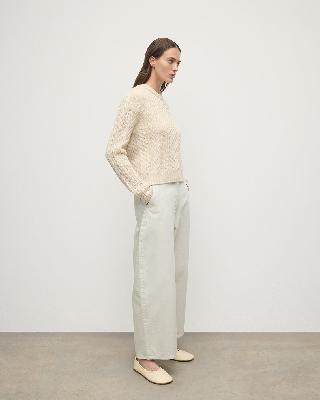 Model wearing Johnstons of Elgin AW25 Women's Knitwear Champagne Aran Cable Cream Cashmere Jumper Side View KAI05086SA0502