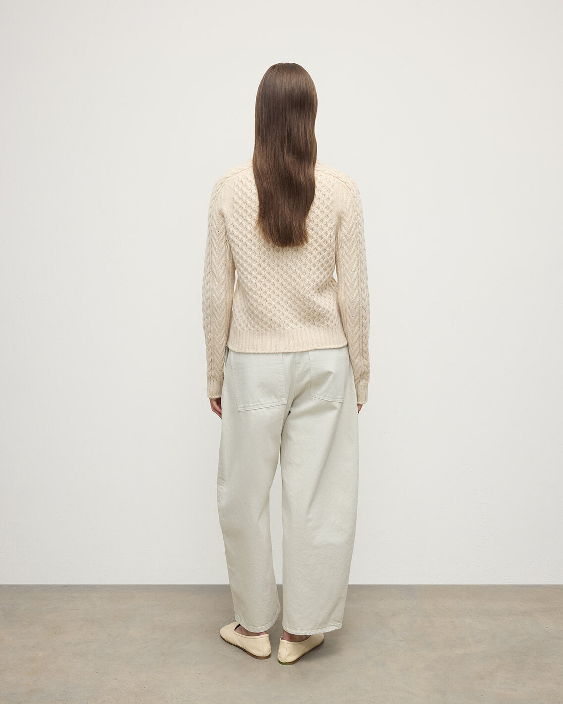 Model wearing Johnstons of Elgin AW25 Women's Knitwear Champagne Aran Cable Cream Cashmere Jumper Back View KAI05086SA0502